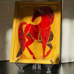 Das leuchtend rote Pferd, Symbol des Jahres 2026, besteht aus unregelmäßigen geometrischen Formen aus strukturierter Paste auf goldenem Grund. Mähne und Schweif des Pferdes leuchten in strahlendem Rot und weisen eine kristalline Struktur auf. Kleine Spiegelausschnitte verstärken die Leuchtkraft des Pferdes.