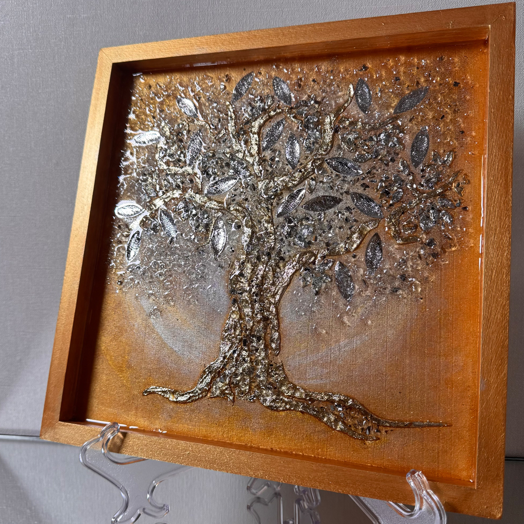 Ein Lebensbaum ist auf goldenem Grund mit Strukturpaste dargestellt. Die Äste und der Stamm sind mit schimmerndem Blattgold überzogen, was dem Gemälde eine glamouröse und prachtvolle Ausstrahlung verleiht. Die Blätter bestehen aus Spiegelglas und sind zusätzlich mit Epoxidharz beschichtet, was ihnen mehr Volumen verleiht und einen Linseneffekt erzeugt. Durch das Zusammenspiel von Licht und Epoxidharzschicht weckt das Gemälde ein Gefühl von Freude und Begeisterung und lädt zum Berühren ein.