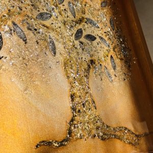 Ein Lebensbaum ist auf goldenem Grund mit Strukturpaste dargestellt. Die Äste und der Stamm sind mit schimmerndem Blattgold überzogen, was dem Gemälde eine glamouröse und prachtvolle Ausstrahlung verleiht. Die Blätter bestehen aus Spiegelglas und sind zusätzlich mit Epoxidharz beschichtet, was ihnen mehr Volumen verleiht und einen Linseneffekt erzeugt. Durch das Zusammenspiel von Licht und Epoxidharzschicht weckt das Gemälde ein Gefühl von Freude und Begeisterung und lädt zum Berühren ein.