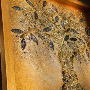 Ein Lebensbaum ist auf goldenem Grund mit Strukturpaste dargestellt. Die Äste und der Stamm sind mit schimmerndem Blattgold überzogen, was dem Gemälde eine glamouröse und prachtvolle Ausstrahlung verleiht. Die Blätter bestehen aus Spiegelglas und sind zusätzlich mit Epoxidharz beschichtet, was ihnen mehr Volumen verleiht und einen Linseneffekt erzeugt. Durch das Zusammenspiel von Licht und Epoxidharzschicht weckt das Gemälde ein Gefühl von Freude und Begeisterung und lädt zum Berühren ein.