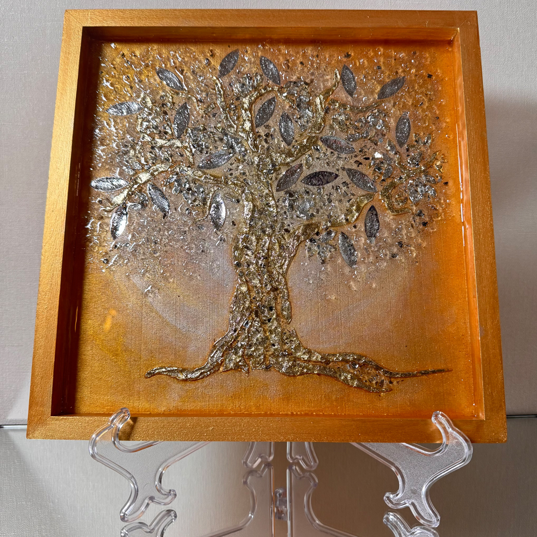 Ein Lebensbaum ist auf goldenem Grund mit Strukturpaste dargestellt. Die Äste und der Stamm sind mit schimmerndem Blattgold überzogen, was dem Gemälde eine glamouröse und prachtvolle Ausstrahlung verleiht. Die Blätter bestehen aus Spiegelglas und sind zusätzlich mit Epoxidharz beschichtet, was ihnen mehr Volumen verleiht und einen Linseneffekt erzeugt. Durch das Zusammenspiel von Licht und Epoxidharzschicht weckt das Gemälde ein Gefühl von Freude und Begeisterung und lädt zum Berühren ein.